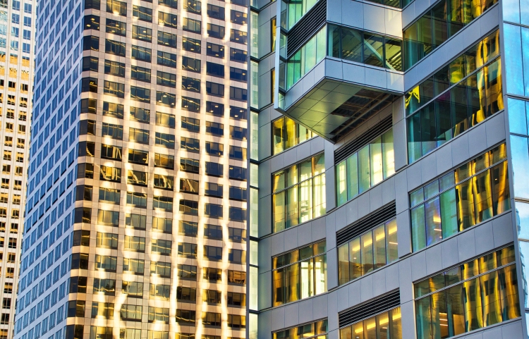 Sides of glass buildings with many windows, reflecting golden sunlight
